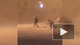 Сильный ветер в Норильске заставляет людей ползти по улице
